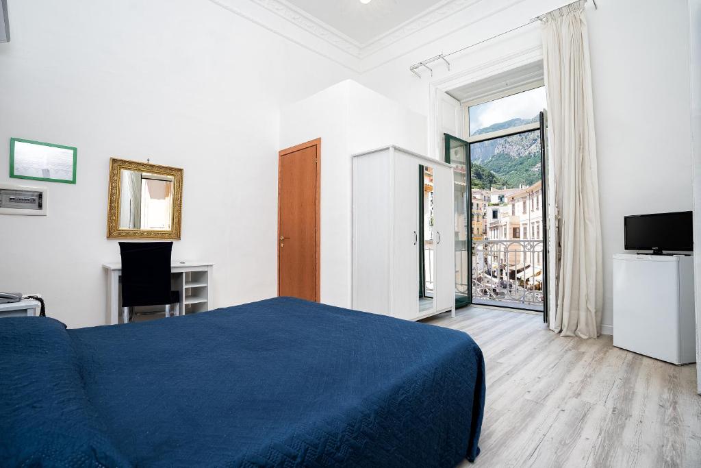 a bedroom with a blue bed and a large window at Hotel Fontana in Amalfi