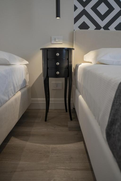 a bedroom with two beds and a nightstand between two beds at Luxmarì Hotel & Spa in Castellammare del Golfo