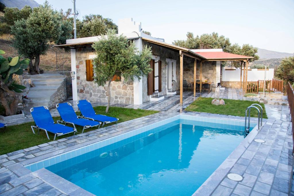 einen Pool mit blauen Stühlen und ein Haus in der Unterkunft Villa Aloni in Triopetra in Triopetra