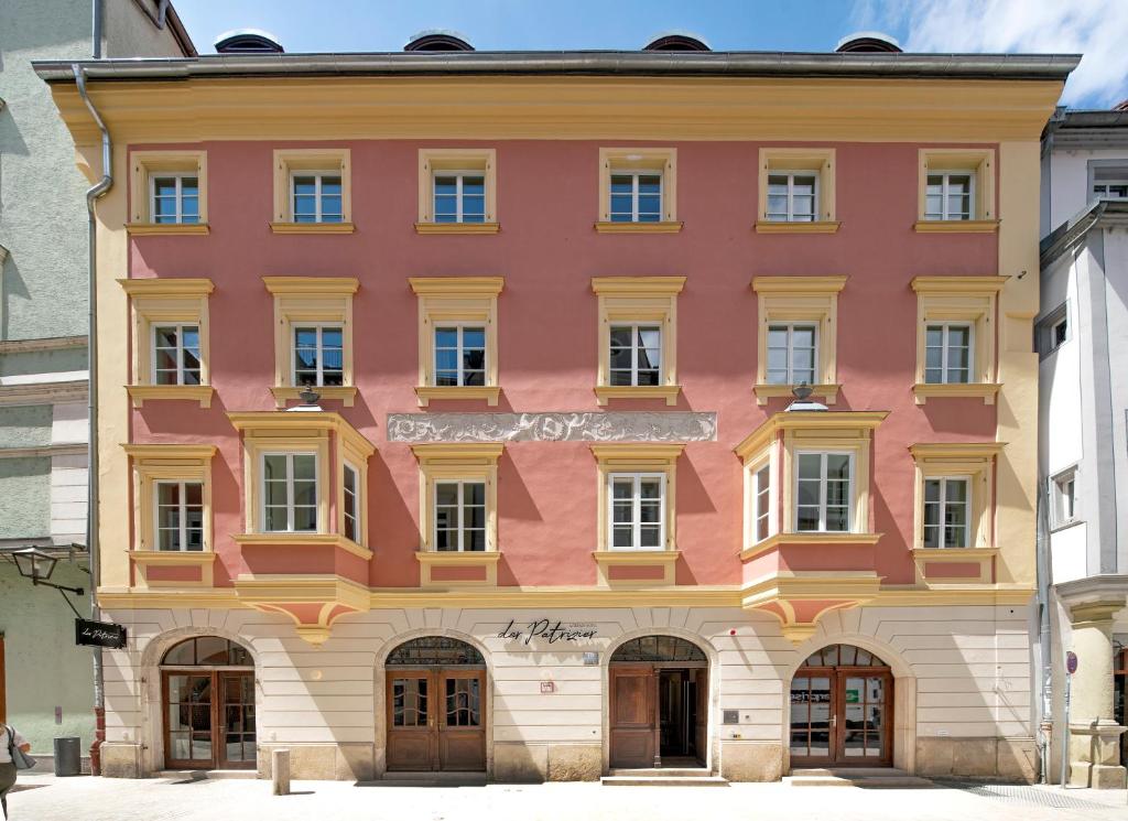 a pink and yellow building in a city at Altstadthotel der Patrizier in Regensburg