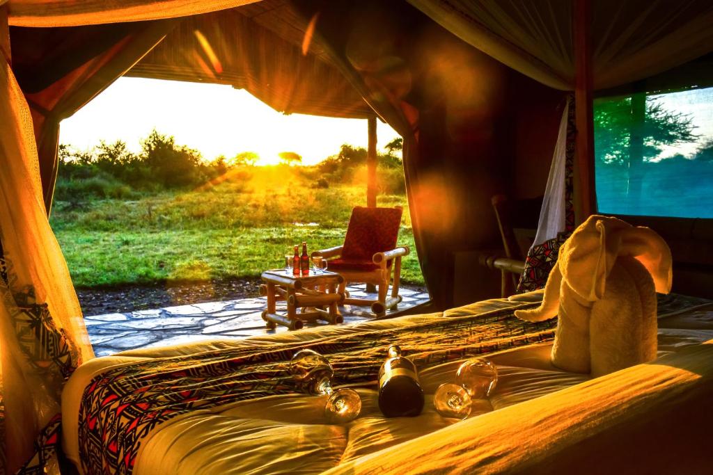 a bedroom with a bed and a chair and a window at Africa Safari Serengeti Ikoma - Wildebeest migration now arrived! in Serengeti