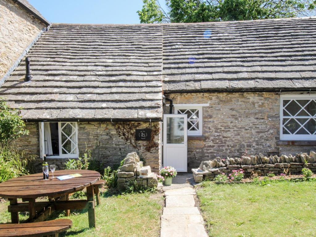 an old stone cottage with a wooden table and bench at Sea Pink Cottage in Swanage