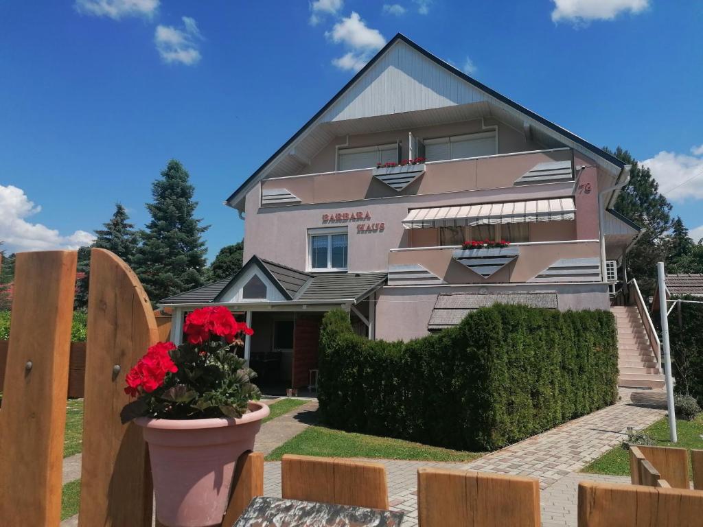 ein rosa Haus mit roten Blumen davor in der Unterkunft Barbara Ház in Hévíz