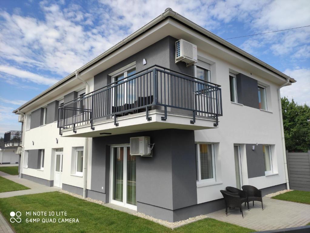 a white building with a balcony and black chairs at Sweet Home Apartments in Sárvár