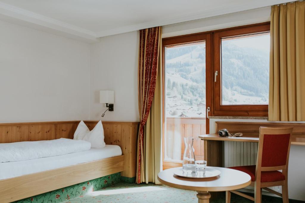 a bedroom with a bed and a table and a window at Hotel Tauernhof in Grossarl