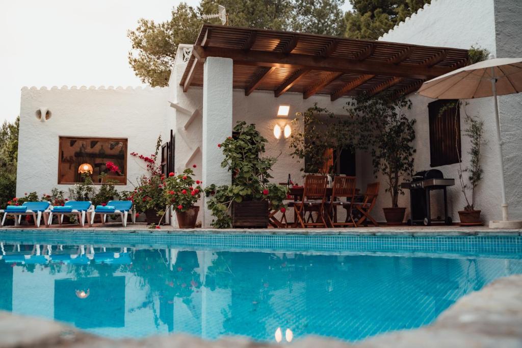 a house with a swimming pool and an umbrella at Villa en Cala Morell con piscina privada en el bosque in Cala Morell