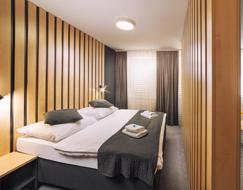 um quarto com uma cama grande e lençóis brancos em TIMEOUT City Hotel em Liptovský Mikuláš