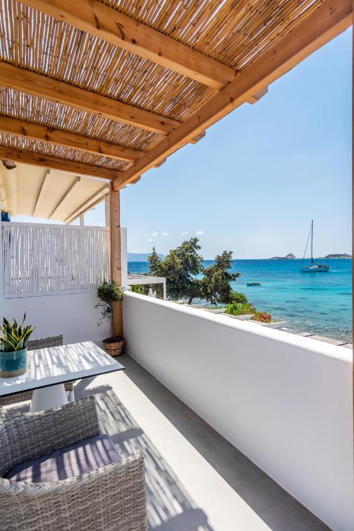 an outdoor patio with a table and chairs and the ocean at Michalakis Seaside Suites in Pollonia