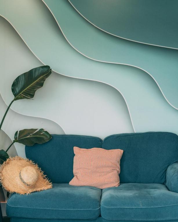 a blue couch in front of a wall with a sculpture at Oceanside Lifestyle Hotel in Newquay