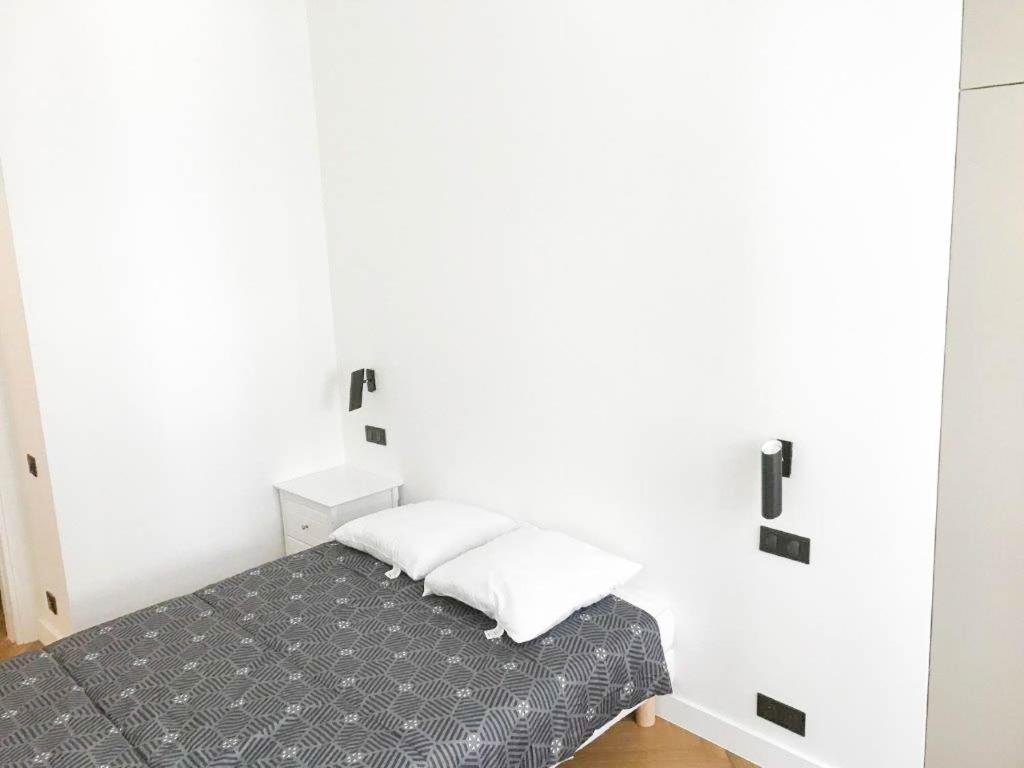 1 dormitorio con cama y pared blanca en Buffa Résidence, en Niza