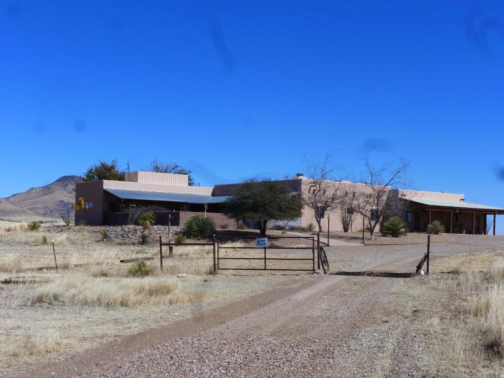 um edifício com uma cerca em frente a uma estrada de terra batida em Rancho Milagro Bed & Breakfast em Elgin