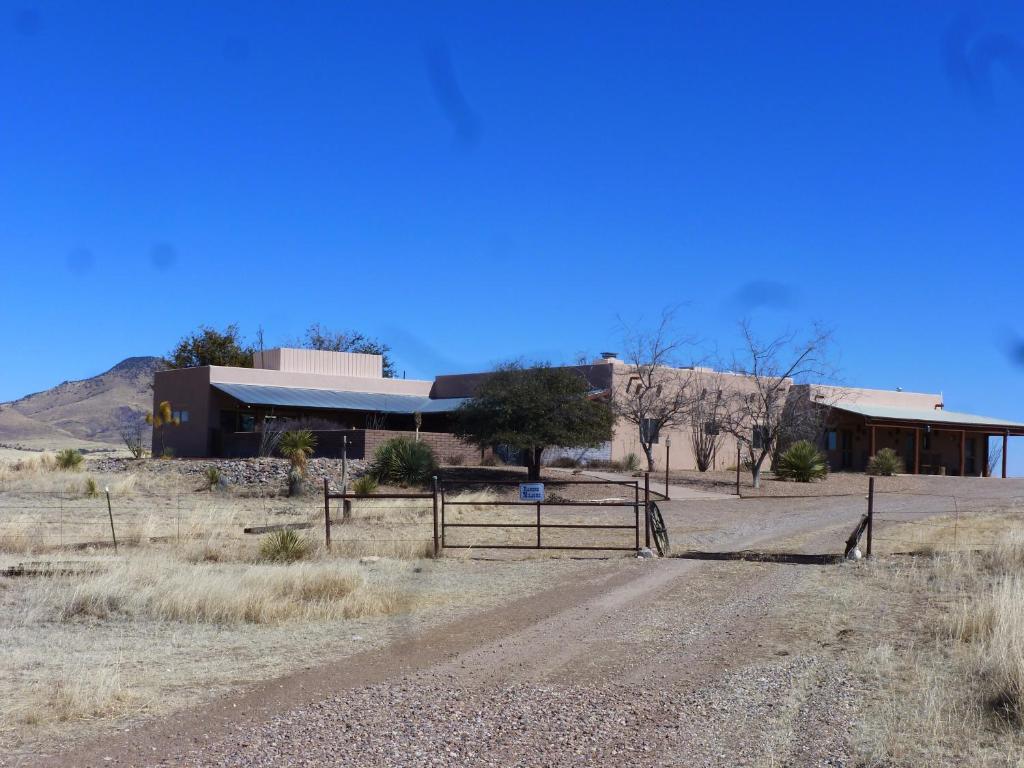 a building with a fence in front of a dirt road at Rancho Milagro Bed & Breakfast in Elgin