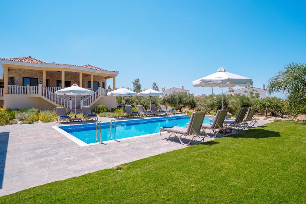 a villa with a swimming pool with chairs and umbrellas at Andrea Villa by Prestige Bookings in Peyia