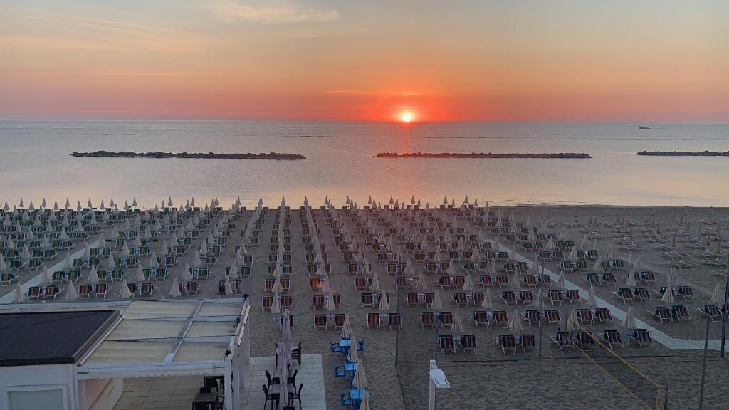 a view of a beach with the sun setting over the water at HOTEL FLYING in Pesaro