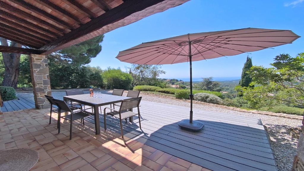 une table et des chaises avec un parasol sur une terrasse dans l'établissement Villa Cigaloun, à La Croix-Valmer