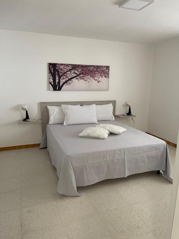 1 dormitorio con 1 cama blanca grande y una pintura en la pared en Sine tempore beach holiday home, en Maruggio