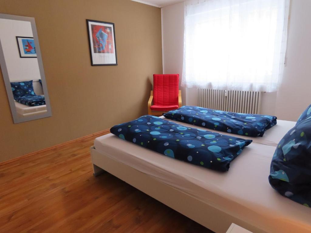 een kamer met een bed en een rode stoel bij Ferienwohnung Berndes in Meersburg
