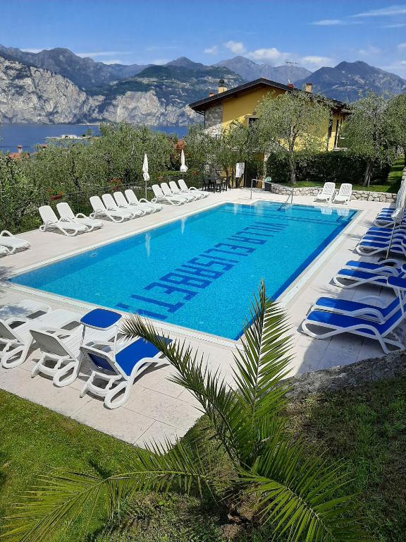 a large swimming pool with lounge chairs at Appartamenti Elisabeth in Brenzone sul Garda