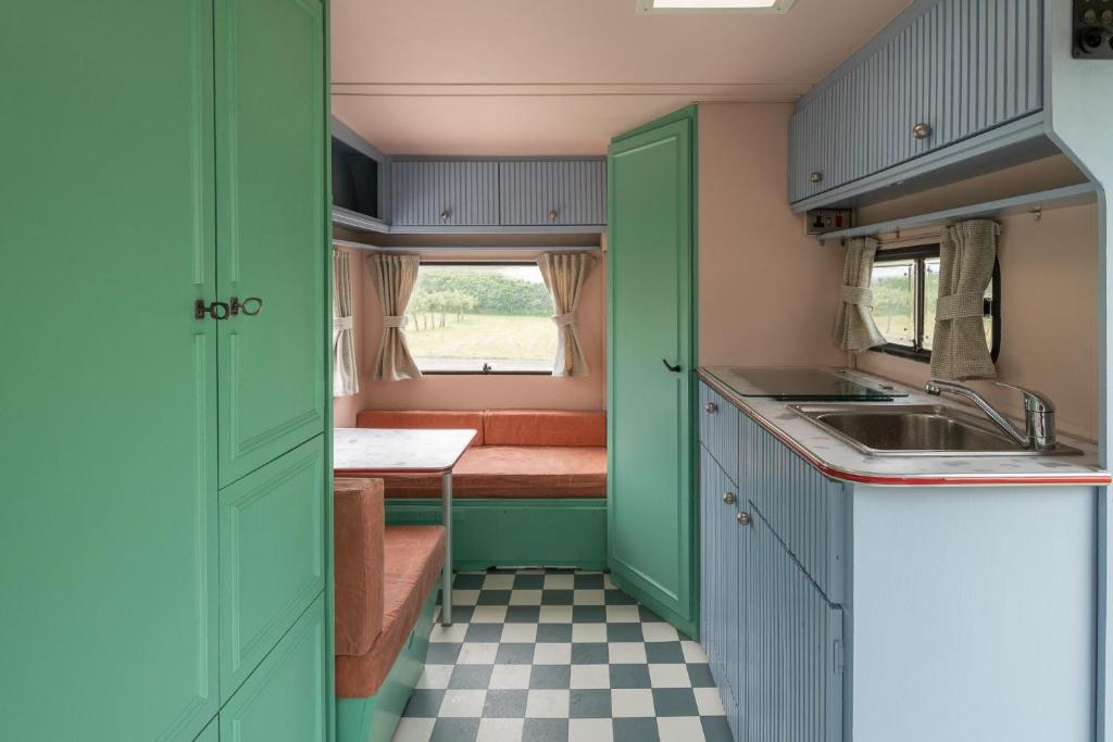 a small kitchen with green cabinets and a sink at Beverley Thrills Caraglamping in Stratford-upon-Avon