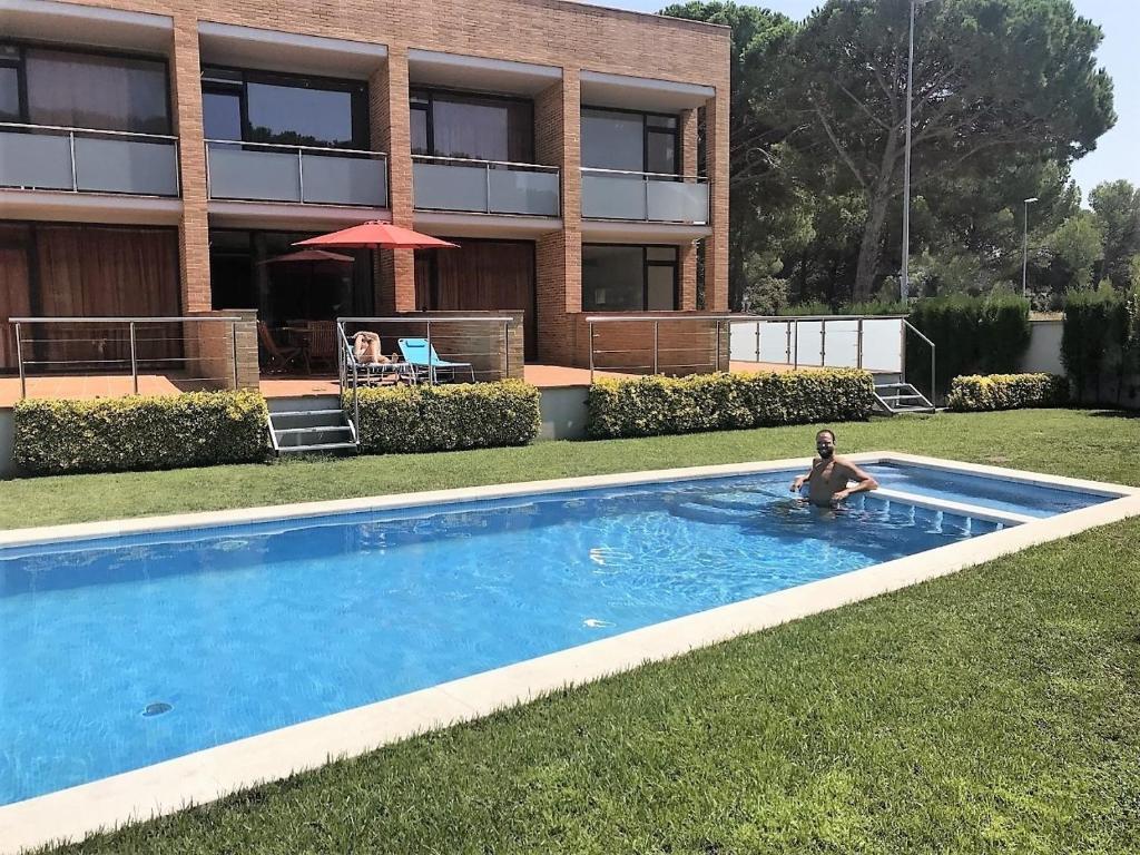 a person in a swimming pool in front of a building at Villa Mar Air conditioning ,Parking in L'Escala