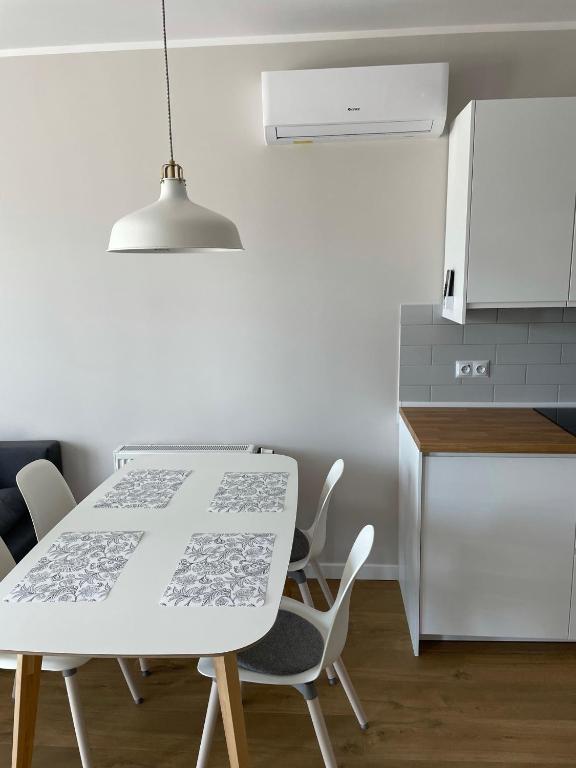 kuchnia z białym stołem i krzesłami oraz lodówką w obiekcie Gąski Apartament Nadmorski w Gąskach