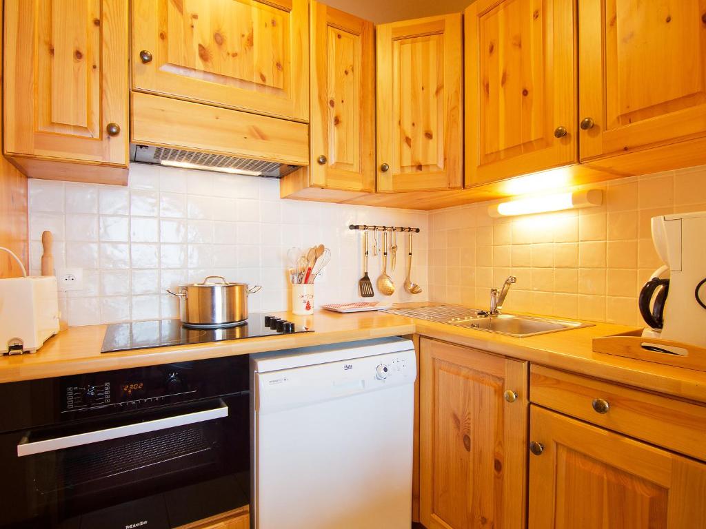 cocina con armarios de madera y lavavajillas blanco en Apartment Origanes 525 by Interhome, en Les Menuires