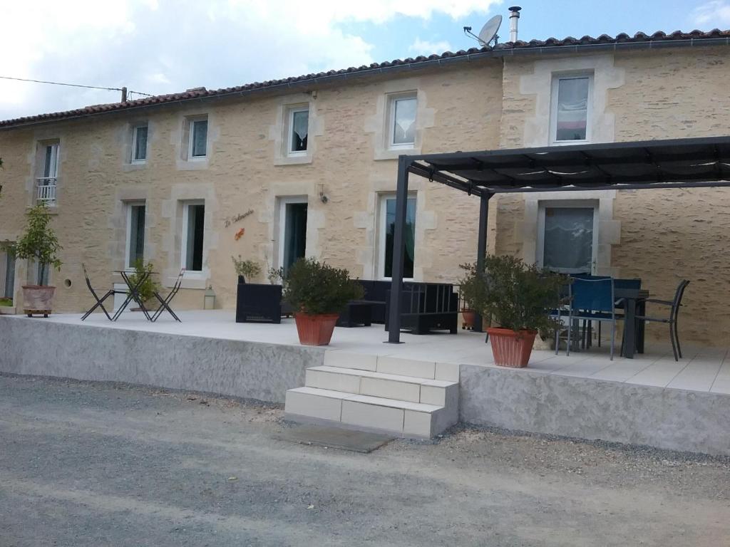 un edificio con un patio con una mesa y plantas en La Salamandre, en Le Busseau