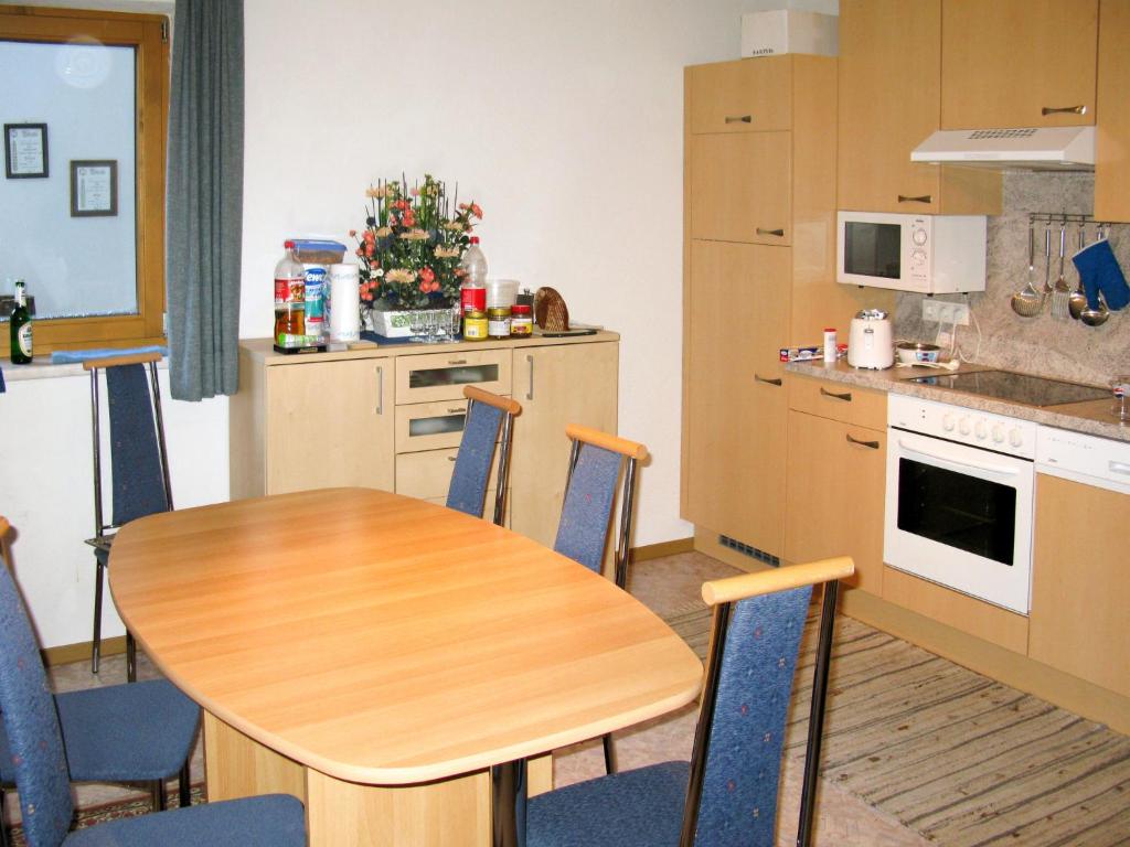 una cucina con tavolo in legno e sedie blu di Apartment Babsi by Interhome a Ginzling