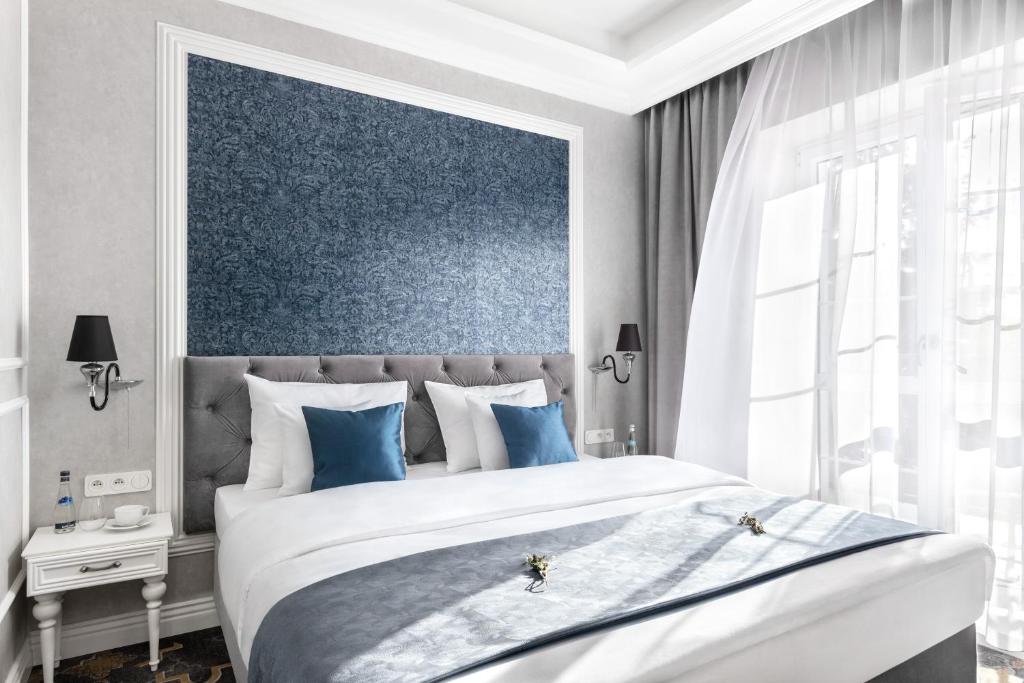 sypialnia z dużym łóżkiem z niebieską ścianą w obiekcie Merci Boutique Hotel w Krakowie