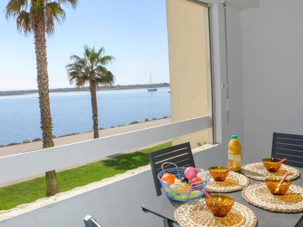 een tafel met uitzicht op de oceaan en palmbomen bij Apartment Les Occitanes by Interhome in Gruissan