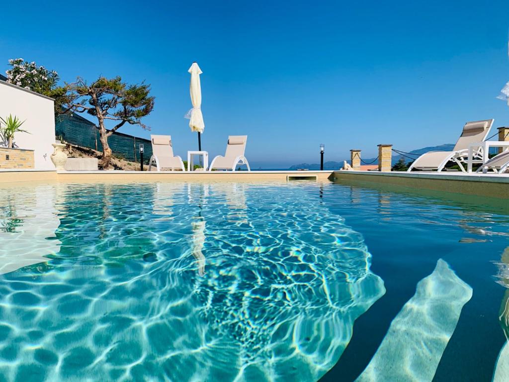 una piscina con sillas y sombrilla en Casa Oleandri en Tresnuraghes