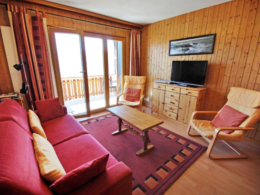 ein Wohnzimmer mit einem roten Sofa und einem Tisch in der Unterkunft Apartment Beausoleil H by Interhome in Veysonnaz
