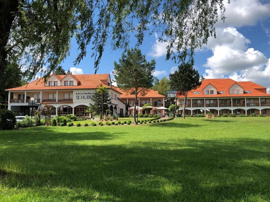 un grand bâtiment avec une pelouse devant lui dans l'établissement Hotel Saint-Hubert, à Hambach