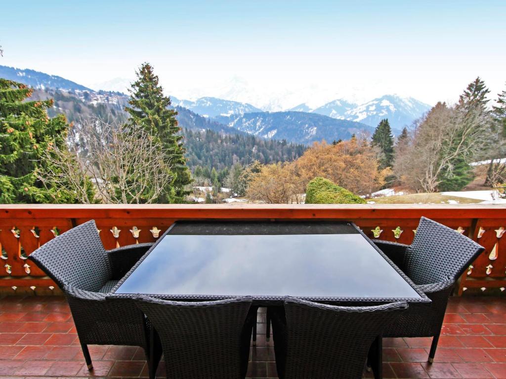 a table and chairs on a balcony with mountains at Apartment Le Geteillon 4 by Interhome in Chesières
