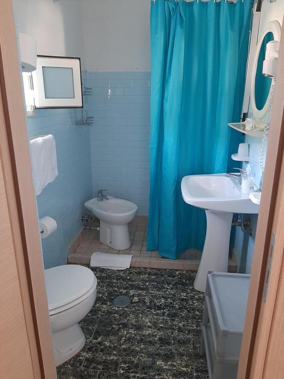 a bathroom with a blue shower curtain and a toilet and sink at Hotel Conca d'Oro in Stalettì