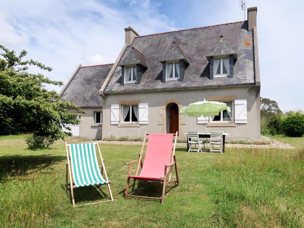 two chairs and an umbrella in front of a house at Holiday Home Les Genêts by Interhome in Plomeur