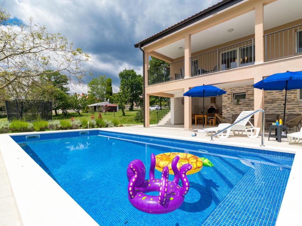 a swimming pool with a purple inflatablevisor in front of a house at Holiday Home Marina by Interhome in Labin
