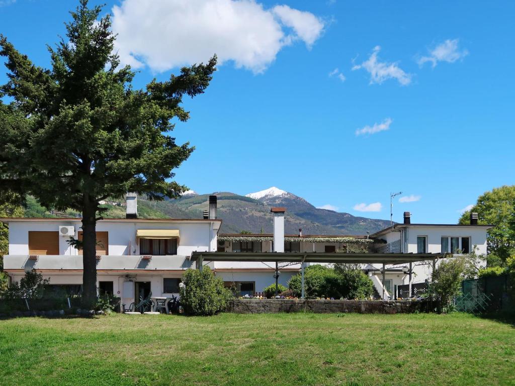 a building with a tree and a mountain in the background at Apartment La Madonnina by Interhome in Domaso