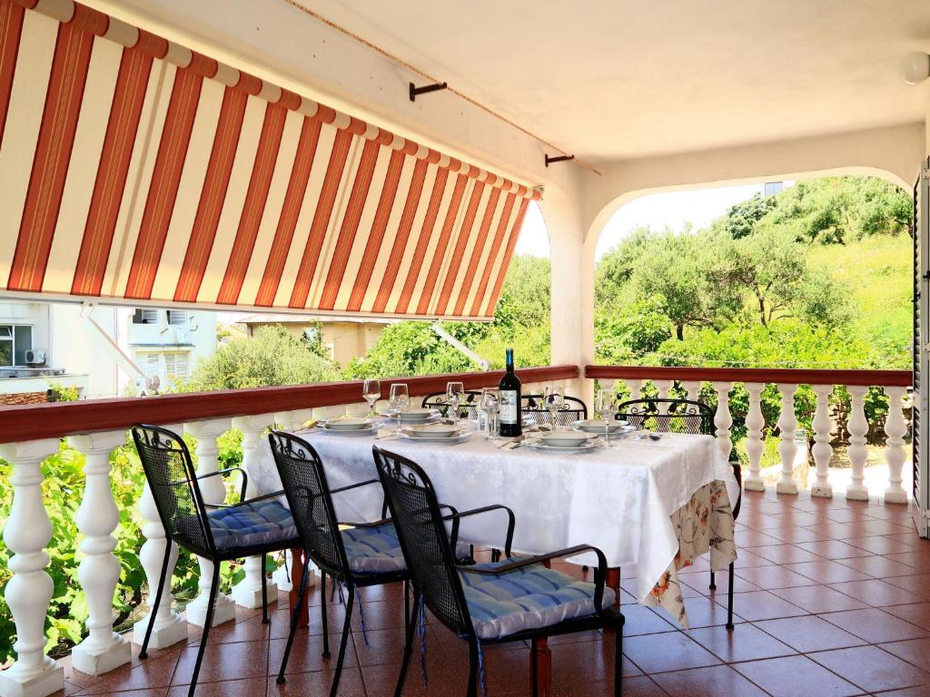 - une table sur un balcon avec une nappe et des chaises blanches dans l'établissement Apartment Dorka - RAB303 by Interhome, à Rab