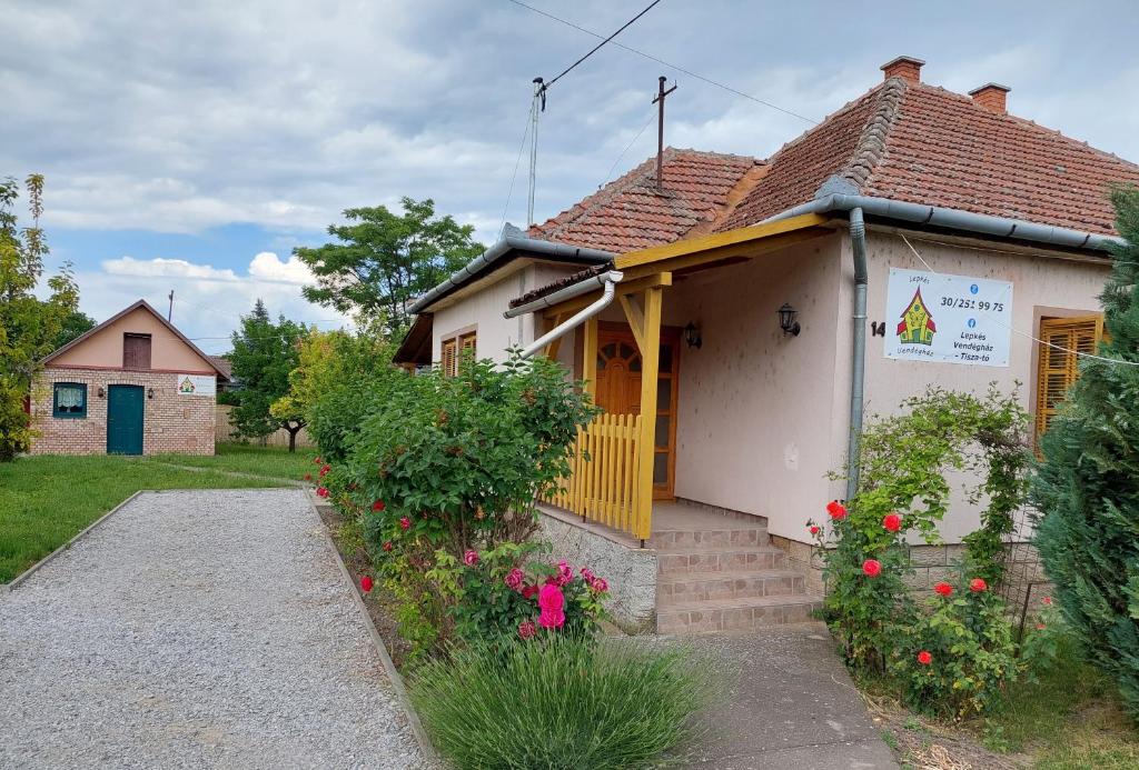 a small house with a yellow door and some flowers at Lepkés Vendégház in Poroszló