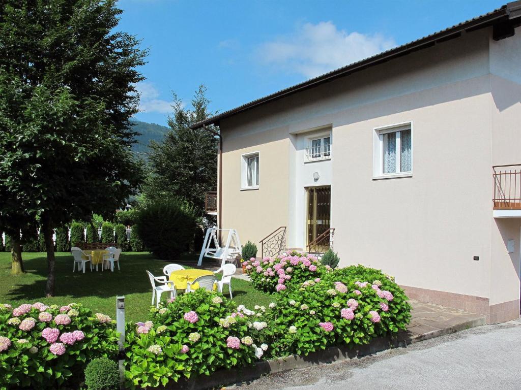 a white house with pink flowers in the yard at Apartment Brida by Interhome in Caldonazzo