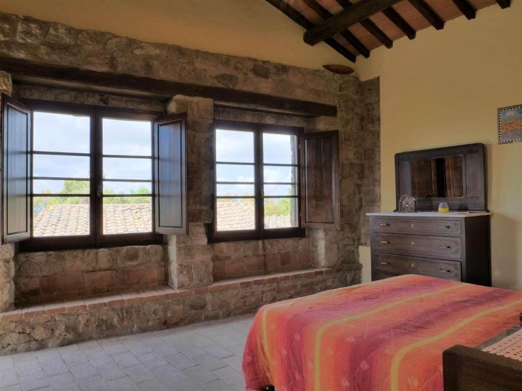 sypialnia z oknami, łóżkiem i komodą w obiekcie Apartment Torretta - Borgo la Civitella by Interhome w mieście Roccastrada