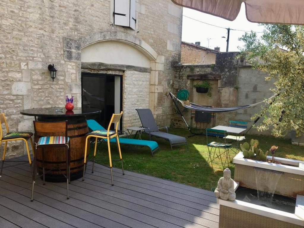 un patio con mesa y sillas en una terraza en Le Nid de Sigogne en Sigogne