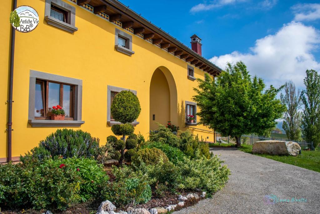 una casa gialla con un giardino di fronte di Antiche Vie B&B a Serramazzoni