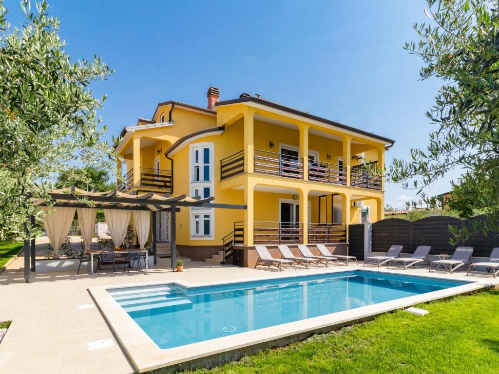 a yellow house with a swimming pool in front of it at Holiday Home Jadranka by Interhome in Novigrad Istria