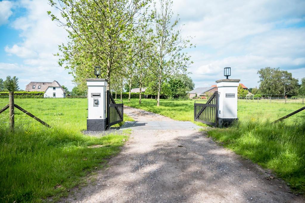 a dirt road with two gates in a field at B&B de Scherpenhof in Leur
