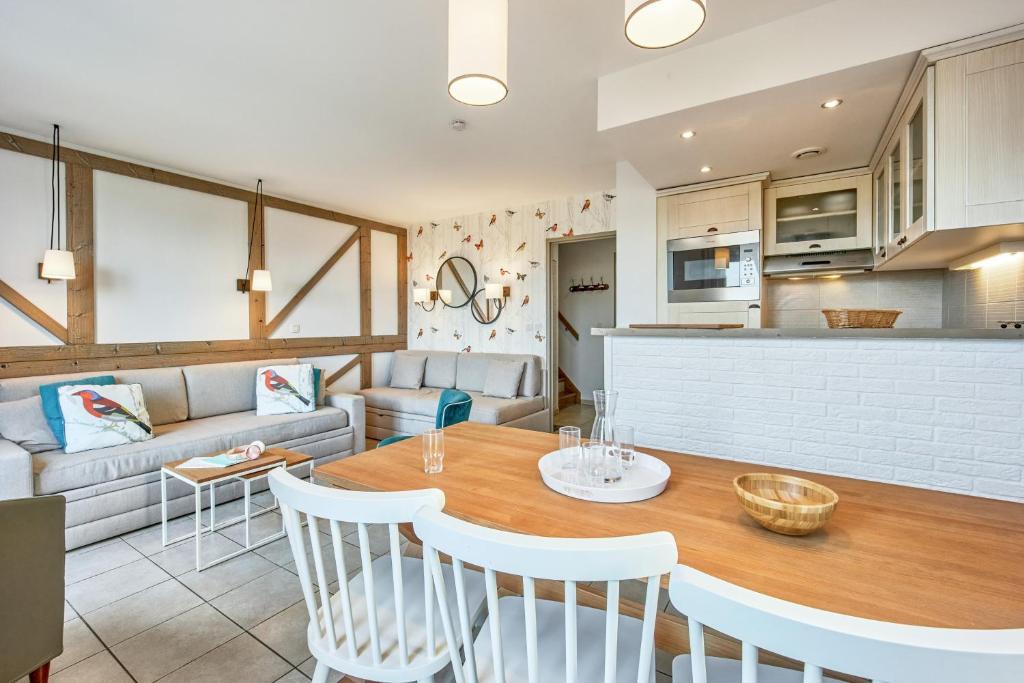 a kitchen and living room with a table and chairs at Pierre & Vacances Premium Residence & Spa Houlgate in Houlgate