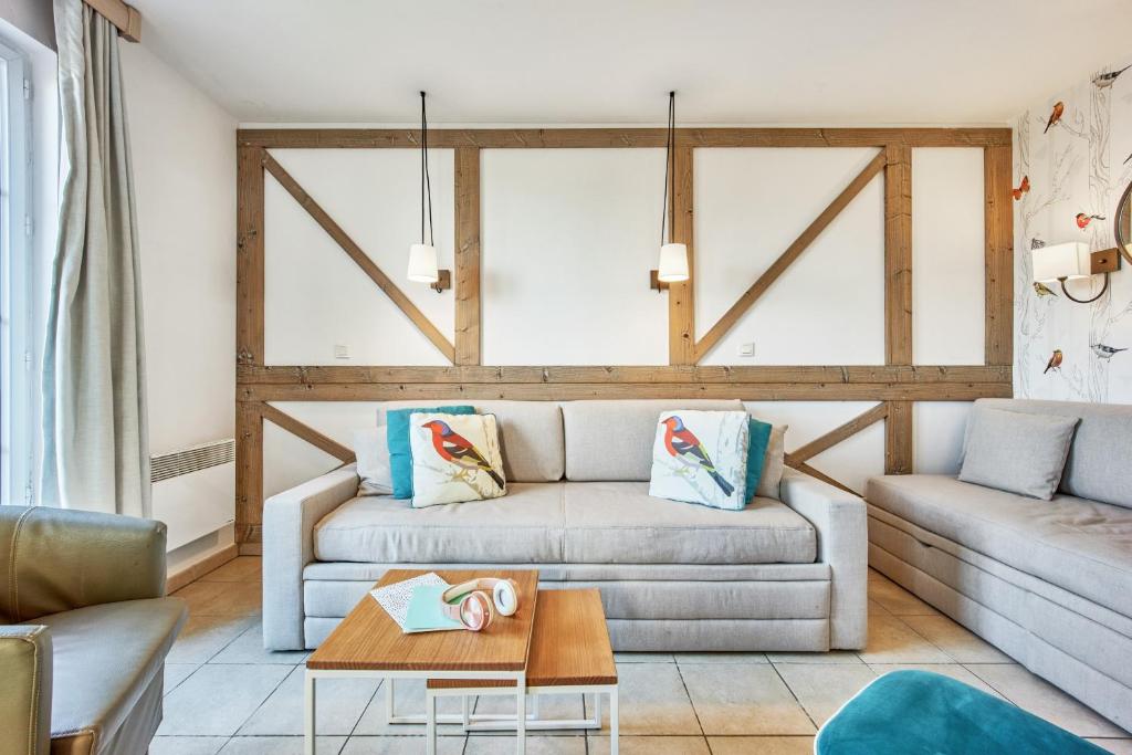 a living room with a couch and a table at Pierre & Vacances Premium Residence & Spa Houlgate in Houlgate