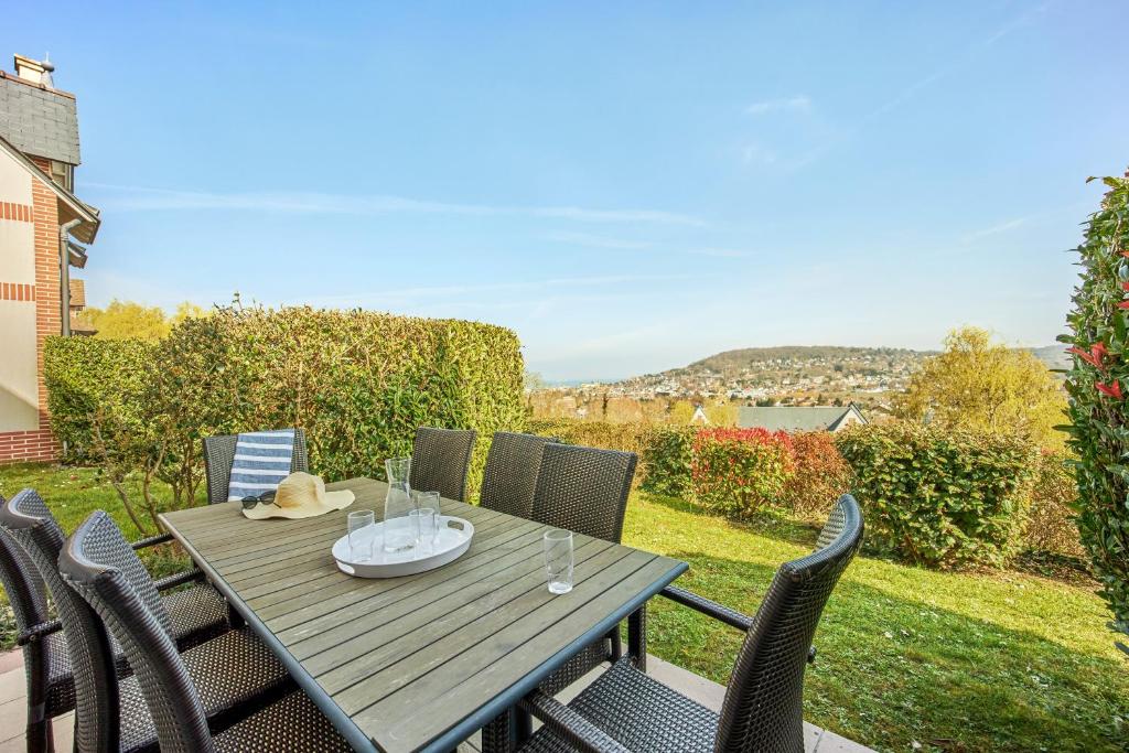 a wooden table and chairs on a patio at Pierre & Vacances Premium Residence & Spa Houlgate in Houlgate