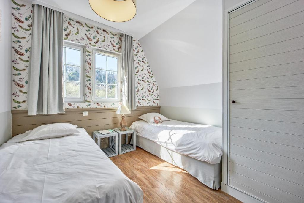 a bedroom with two beds and a window at Pierre & Vacances Premium Residence & Spa Houlgate in Houlgate